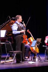 ENSEMBLE VIVANT in concert at Regent Theatre, Oshawa, ON, May 24, 2018. Launch of telMAX/Euterpe/Yamaha partnership in the Durham Region.  Ensemble Vivant’s violinst Corey Gemmell speaking to audience; not in view:  Jim Vivian, bass; Catherine Wilson, piano; Sybil Shanahan, cello; Norman Hathaway, viola.  Photo by Marion Voysey